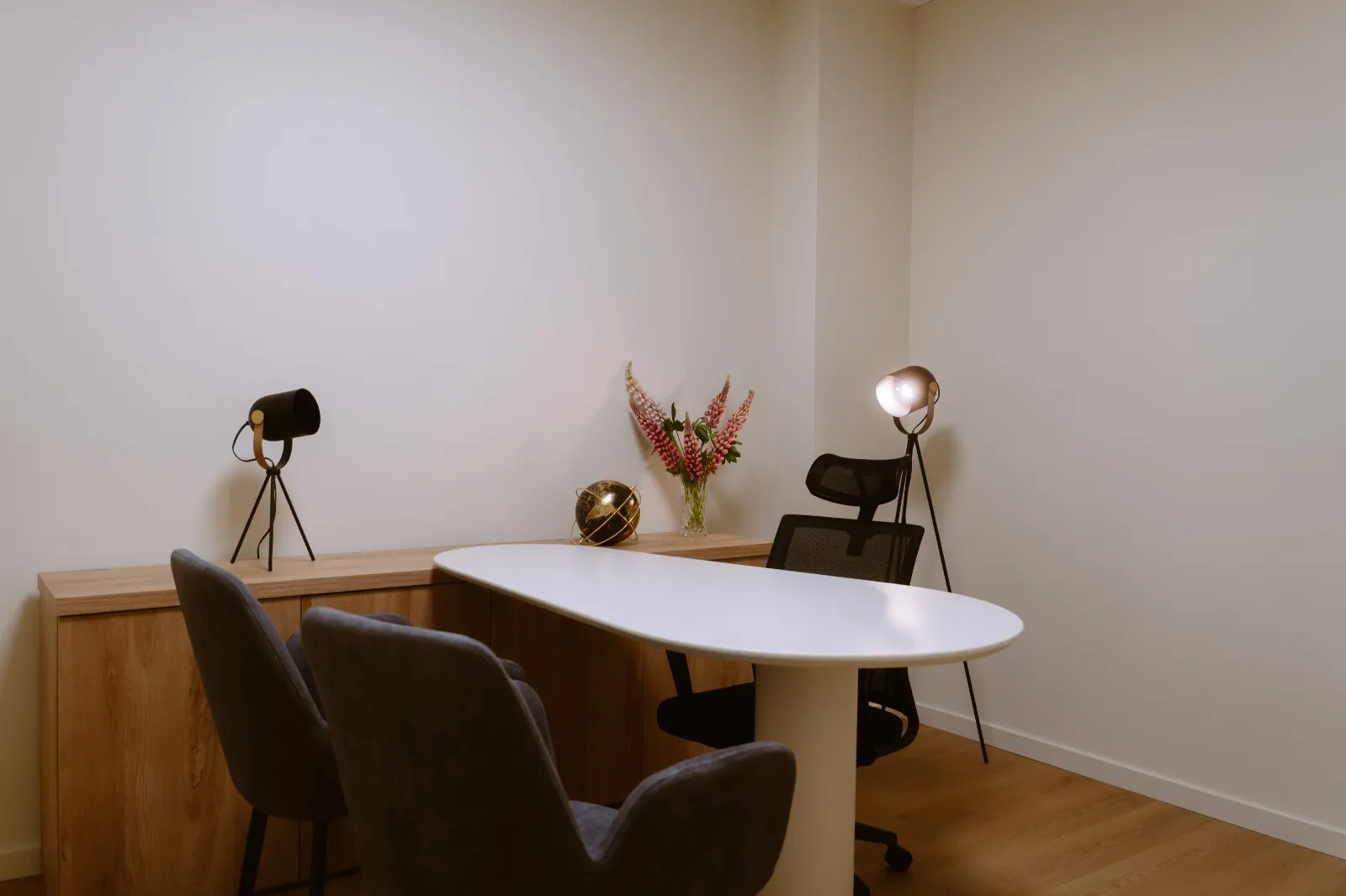 Sala de consulta com candeeiros de pé e flores sobre o móvel
